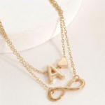 Double layer ankle bracelet featuring an infinity symbol and a letter A charm on a woman's ankle.