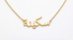 Copper necklace pendant spelling the name "Skina" in Arabic calligraphy