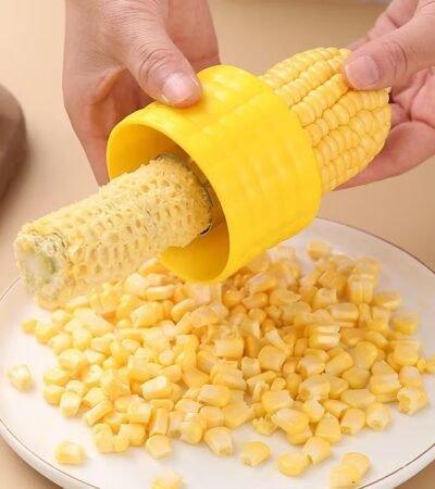 A person using the Stainless Steel Corn Stripper Peeler on a yellow corn cob.