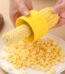 A person using the Stainless Steel Corn Stripper Peeler on a yellow corn cob.