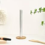 A standing light-colored wooden paper towel holder standing on a kitchen counter.