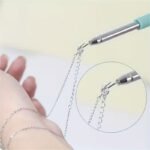 Retractable jewelry helper tool holding a gold bracelet for easy fastening.