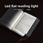 A transparent LED reading light panel placed over a paperback book page in a dark room.
