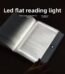 A transparent LED reading light panel placed over a paperback book page in a dark room.