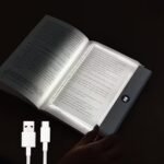 A transparent LED reading light panel placed over a paperback book page in a dark room.