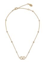 Close-up of Valentino Garavani Mini VLogo pendant with Swarovski crystals on a metal chain.