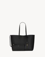 Saint Laurent East/West black leather tote bag with gold YSL charm and detachable pouch.
