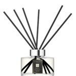 Sleek glass citrus diffuser bottle with 10 black reeds on a minimalist background.