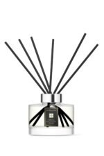 Sleek glass citrus diffuser bottle with 10 black reeds on a minimalist background.