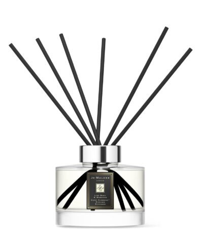 Sleek glass citrus diffuser bottle with 10 black reeds on a minimalist background.